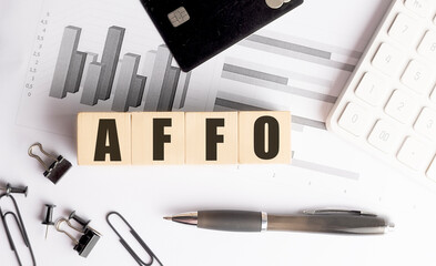 Poster -  Wooden blocks with the abbreviation AFFO on a desk with financial charts, a black credit card