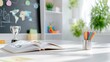 © Bella - Open book and colored pencils on a white desk in a bright classroom with a blackboard and trophy in the background.