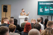 © Anton Gvozdikov - Speaker delivers presentation to attentive audience at business event. Large screen displays data on stage. Professional setting promotes learning and networking among attendees.