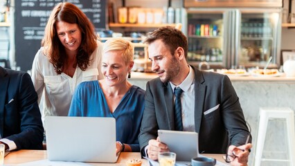 Aufkleber - Group of business professionals collaborating in a cafe. Diverse people discussing work. Laptops and tablets in use. Casual meeting in a modern cafe, diverse business team discussing ideas