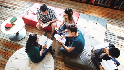 Poster - Group of young adults studying together in a library. Young adults reading books, using tablets. Diverse group of young adults, studying in a library. High school international students, education.