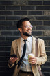 © Zamrznuti tonovi - Smiling businessman holding coffee and using smartphone