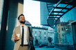 © Zamrznuti tonovi - Businessman holding coffee walking outside modern office building