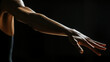 © Azamat - Elegant arm reaching out toward the light in a dramatic low-light setting during a dance performance