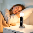 © Alexandra - Modern digital alarm clock lamp on bedside table near sleeping young lady in morning at home, selective focus on lighting gadget