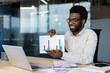 © Liubomir - Remote online presentation, male financier shows graph and income chart into laptop camera. Businessman smiles with satisfaction, winning results of enterprise achievements, successful investments.