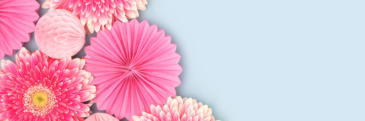 Wall Mural - banner with pink gerbera flowers, tissue paper fans and balls on a blue background. place for text.
