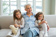 © Юлия Завалишина - Happy family at home. Two little girls sisters twins grandmother enjoying time together. Good time at home. Grandma granddaughters child kids emotional bonding hugging together. Family generations