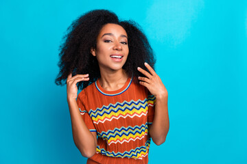 Wall Mural - Photo portrait of beautiful young girl wearing brown ornament stylish t shirt touching black curls isolated on blue color background