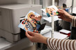 © New Africa - Woman with colorful photos near modern printer indoors, closeup