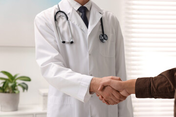 Wall Mural - Doctor shaking hands with patient in hospital, closeup