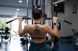 © asier - Female athlete performing lat pull down exercise, strengthening back muscles in contemporary gym, showcasing physical fitness and athletic determination