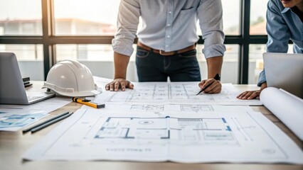 Aufkleber - An engineer discussing plans over a large blueprint with diagrams of reactor components spread out on a table highlighting a collaborative effort.