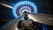 Medium closeup of a worker inspecting a wind turbine blade under bright LED lights highlighting surface imperfections and a clipboard filled with notes.