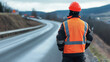 © BURINKUL - Traffic controller standing on a roadside with a reflective jacket and helmet, managing traffic near a freshly paved road