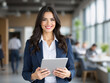 © Nour Studio - Professional portrait of a confident, smiling business woman in a stylish suit, holding a tablet, against a modern office background