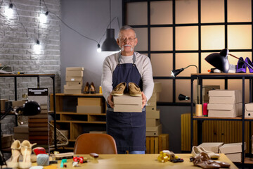 Wall Mural - Mature shoemaker with shoe box in workshop