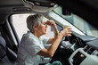 © Davor - Senior female medical professional holding head in stress during coffee break in car