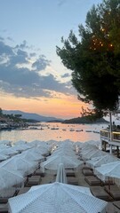 Poster - Scenic beach sunset with white umbrellas and boats.