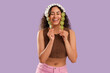 © Pixel-Shot - Beautiful young happy African-American woman holding sticks with kiwi on purple background