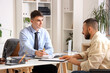 © Pixel-Shot - Young lawyer working with client in wheelchair at office