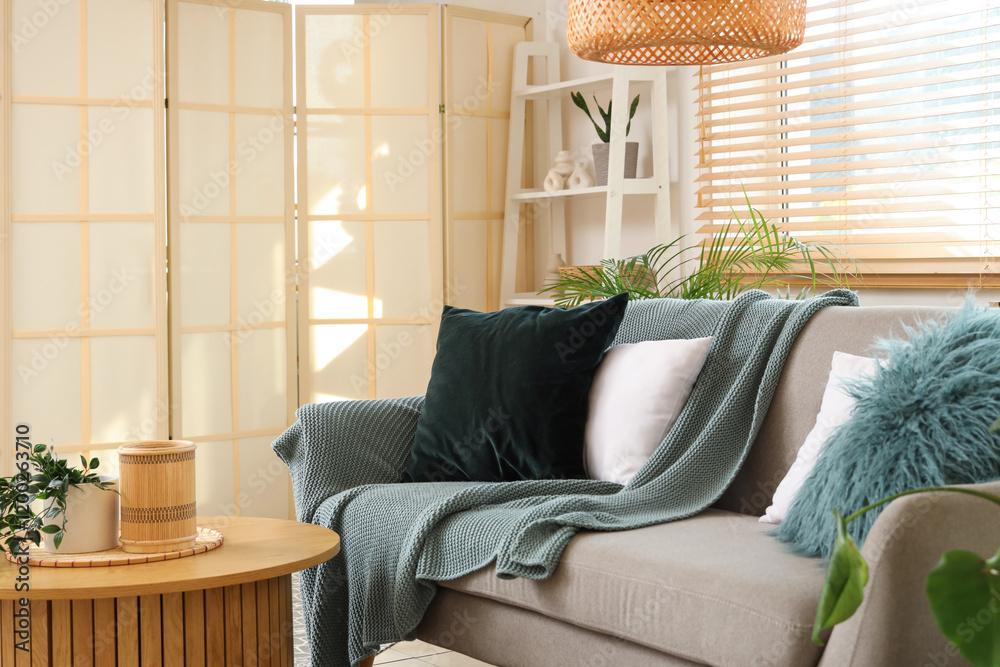Grey sofa with cushions and plaid in light living room