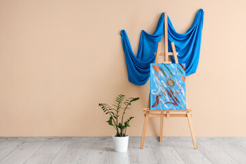 Wall Mural - Painting on easel with houseplant near beige wall