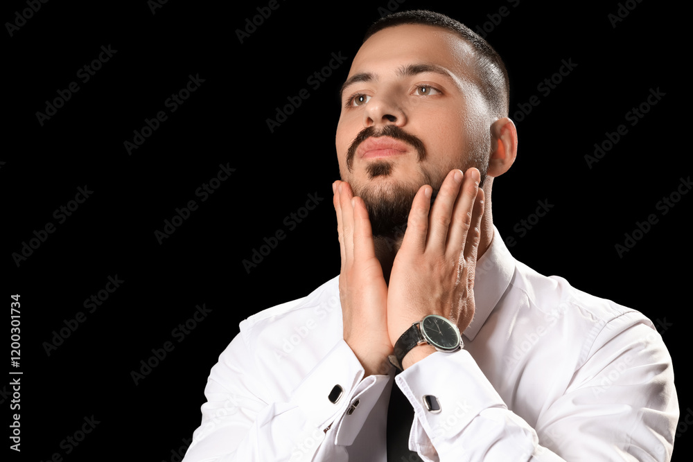 Handsome young bearded man on black background