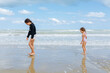 © Victoria - side view of little girls in the swimsuit standing on the beach playing with waves