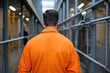 © Milos - A solitary figure in an orange jumpsuit walks down a narrow prison corridor, symbolizing confinement and resilience in a challenging environment for inmates.
