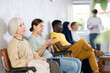 © JackF - Positive carefree elderly woman sitting in lobby of medical clinic and waiting for appointment with doctor