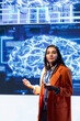 © DC Studio - Presenter talking in front of world leading technology experts and researchers meeting at artificial intelligence conference. Data scientist showcasing latest developments in AI industry