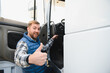© Serhii - Truck driver prepares to climb into the cab of his truck. Concept of transport and deliveries by large vehicles