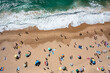 © Andrii - Overhead drone shot of anonymous tourists and parasols on sandy seashore. Directly above view of people enjoying summer vacations at beach during sunny day