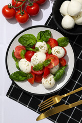 Wall Mural - Caprese salad in a white bowl on a light background