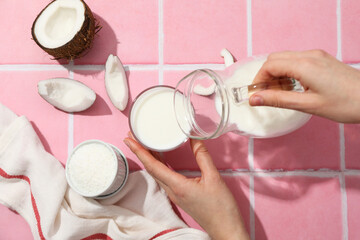 Wall Mural - Coconut milk in a jug on a pink background.