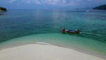 Wall Mural - Enjoy a serene moment on Koh Lipe Thailand tranquil shores, where white sands meet crystal-clear waters. Couples unwind as boats drift by in this idyllic island paradise.