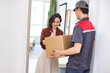 © Blue Jean Images - Delivery person delivering package to the lady