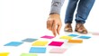 © Nav_ender - Person placing colorful sticky notes on a white background.