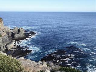 Ocean Waves Crashing Against Rugged Coastal Rocks on a Sunny Day