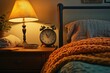 © Sean Hoong - A bedside shelf with a classic analog alarm clock, a lamp, and a cozy blanket nearby.