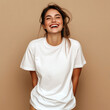 © Alena - Laughing young woman model with messy hairstyle, dressed in white oversized t-shirt standing near plain background, studio shot. Blank short sleeve tee template. Women crewneck basic tshirt mock up