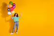 © deagreez - Full size photo of pretty young girl balloons raise fist empty space wear striped t-shirt isolated on yellow color background