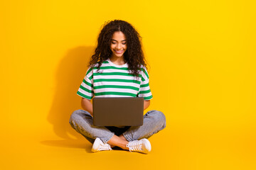 Full body portrait of nice young girl sit floor use laptop wear striped t-shirt isolated on yellow color background