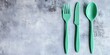 © Valeriia - Mint Green Plastic Cutlery Set on Grey Background