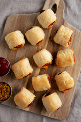 Wall Mural - Homemade Pigs in a Blanket with Ketchup and Mustard on a Wooden Board, top view. Flat lay, overhead, from above.