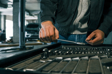 Poster - Close-up of a mechanic's hand picking wrenches from a well-organized tool tray in a workshop. Metal wrenches in various sizes, ready for repair tasks
