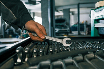 Poster - Mechanic selecting a wrench from a tool tray in a garage, preparing for vehicle maintenance or repair