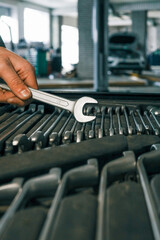 Poster - Close-up of a mechanic's hand picking wrenches from a well-organized tool tray in a workshop. Metal wrenches in various sizes, ready for repair tasks