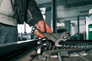 Poster - Close-up of a mechanic's hand picking wrenches from a well-organized tool tray in a workshop. Metal wrenches in various sizes, ready for repair tasks